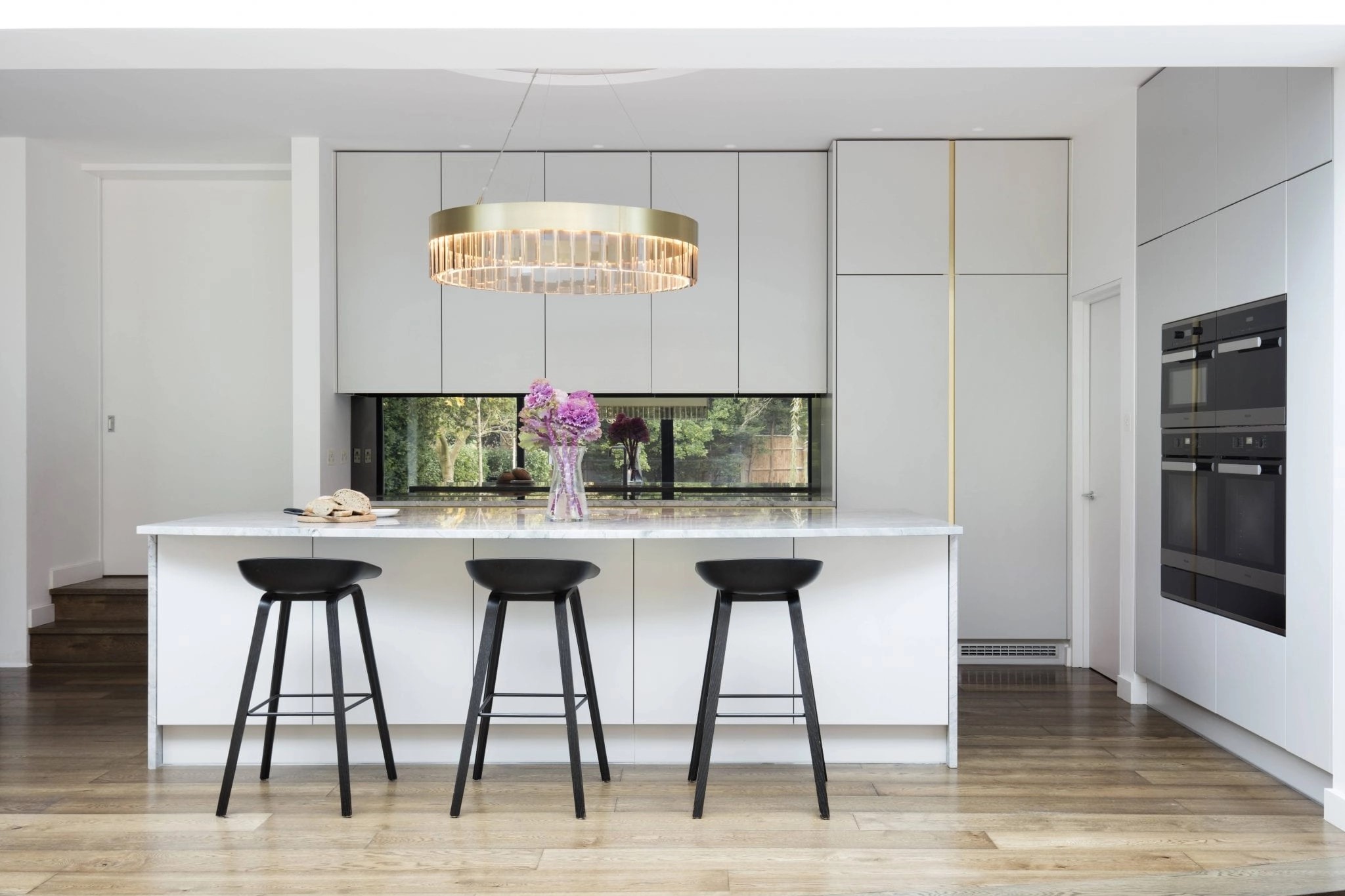 Stylish kitchen with a white island, elegant chandelier, and sleek built-in appliances.